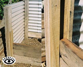 Photograph of a corner section of one bin and a close up of a guide for the removable slats in a compost bin. 